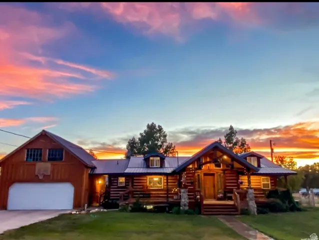 Log-style house with a front yard, a garage, a metal roof, and driveway