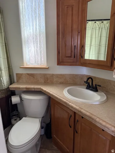 Bath with a shower with curtain, vanity, and dark tile patterned flooring