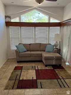 Living area with healthy amount of natural light, a ceiling fan, light tile patterned floors, and high vaulted ceiling