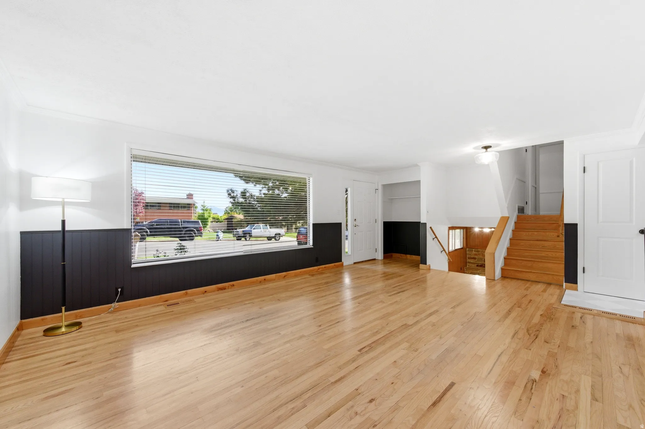 Unfurnished living room featuring a wainscoted wall, light wood-style flooring, crown molding, and wooden walls