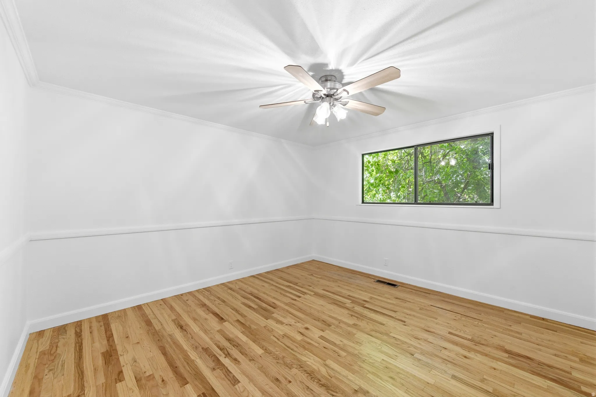 Empty room with light wood-type flooring, ornamental molding, and a ceiling fan