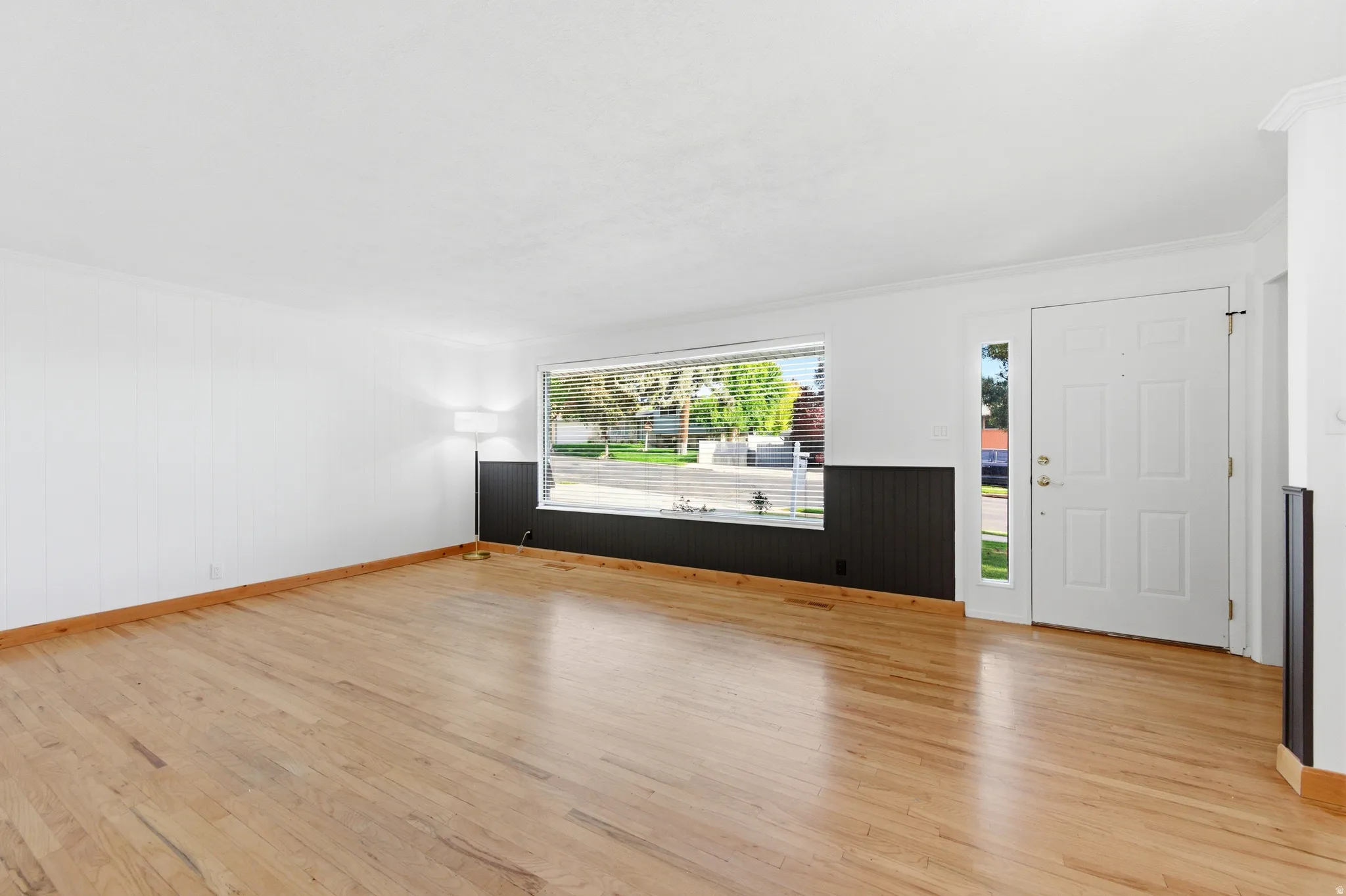 Foyer with light wood-style floors, ornamental molding, and wooden walls