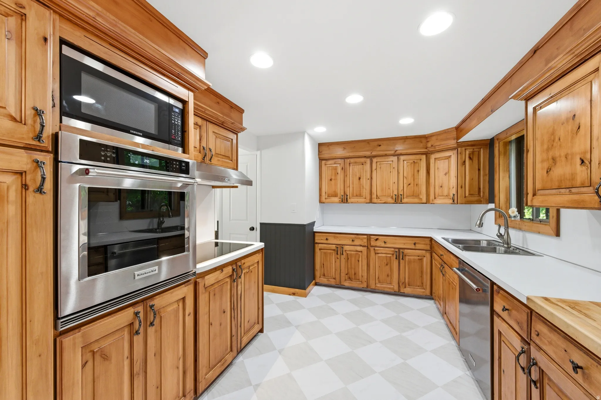 Kitchen featuring light floors, stainless steel appliances, light countertops, wood finish cabinetry, and recessed lighting