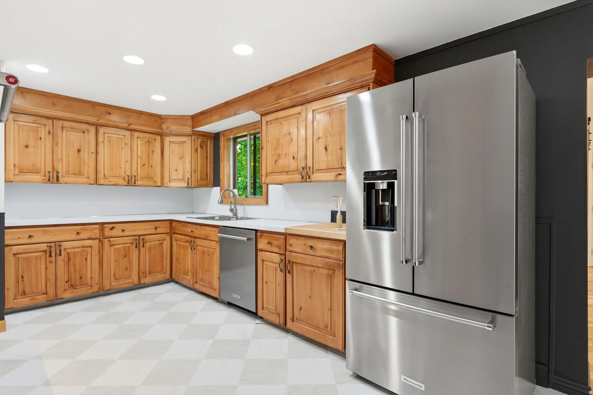 Kitchen featuring light flooring, light countertops, stainless steel appliances, recessed lighting, and wood finish cabinets