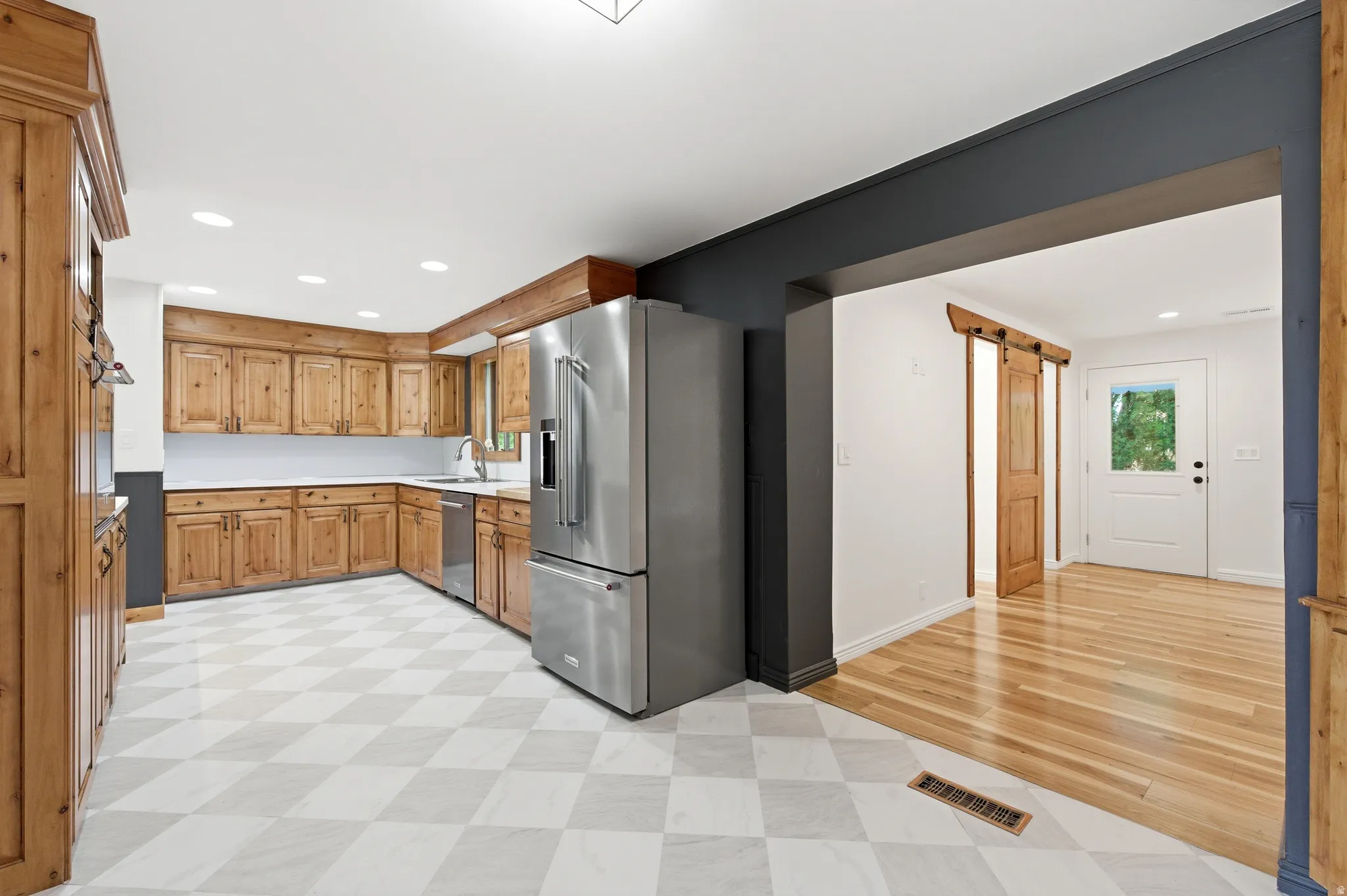 Kitchen featuring stainless steel appliances, light countertops, a barn door, recessed lighting, and light flooring