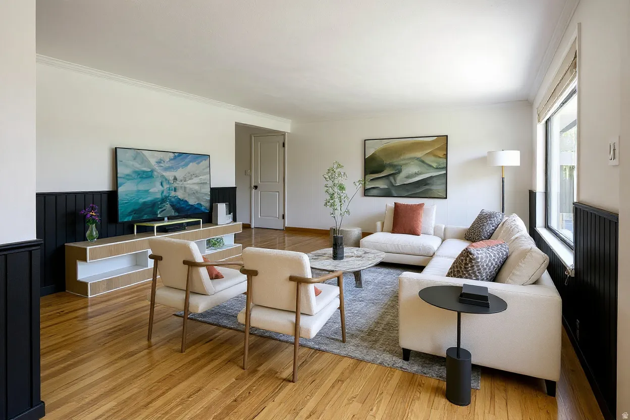 Spacious living area featuring wood-finish flooring, white walls with dark wainscoting, and large windows