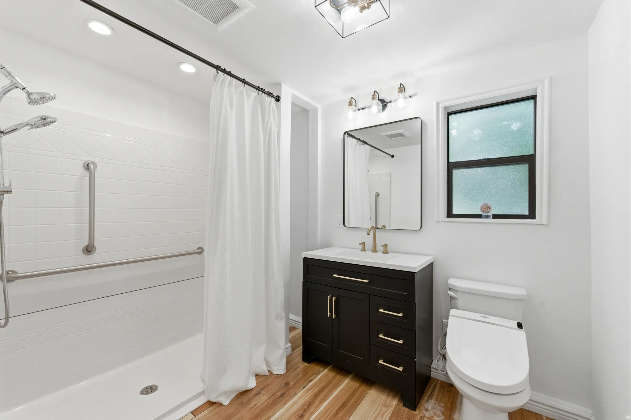 Bathroom featuring vanity, light wood-style flooring, a shower stall, and recessed lighting