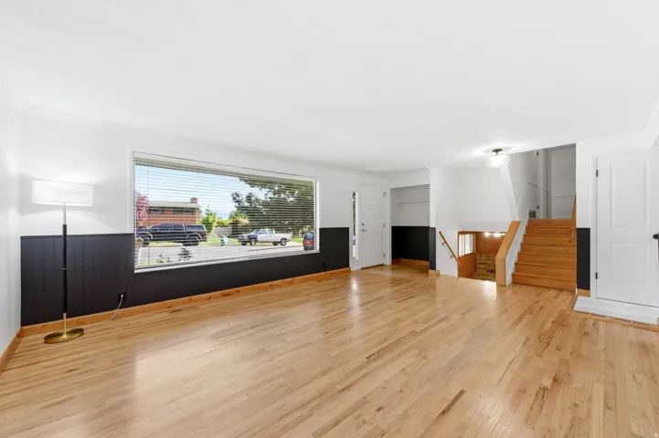 Unfurnished living room featuring a wainscoted wall, light wood-style flooring, crown molding, and wooden walls