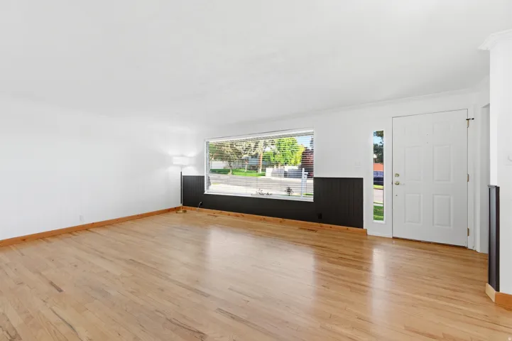 Foyer with light wood-style floors, ornamental molding, and wooden walls