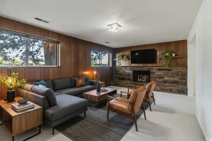 Living area featuring wood paneling, a stone fireplace with hearth, and recessed lighting