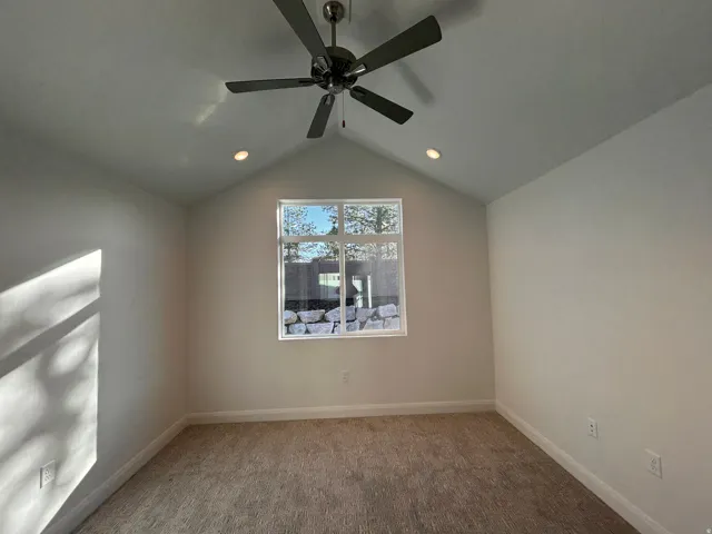 Carpeted spare room with baseboards and vaulted ceiling