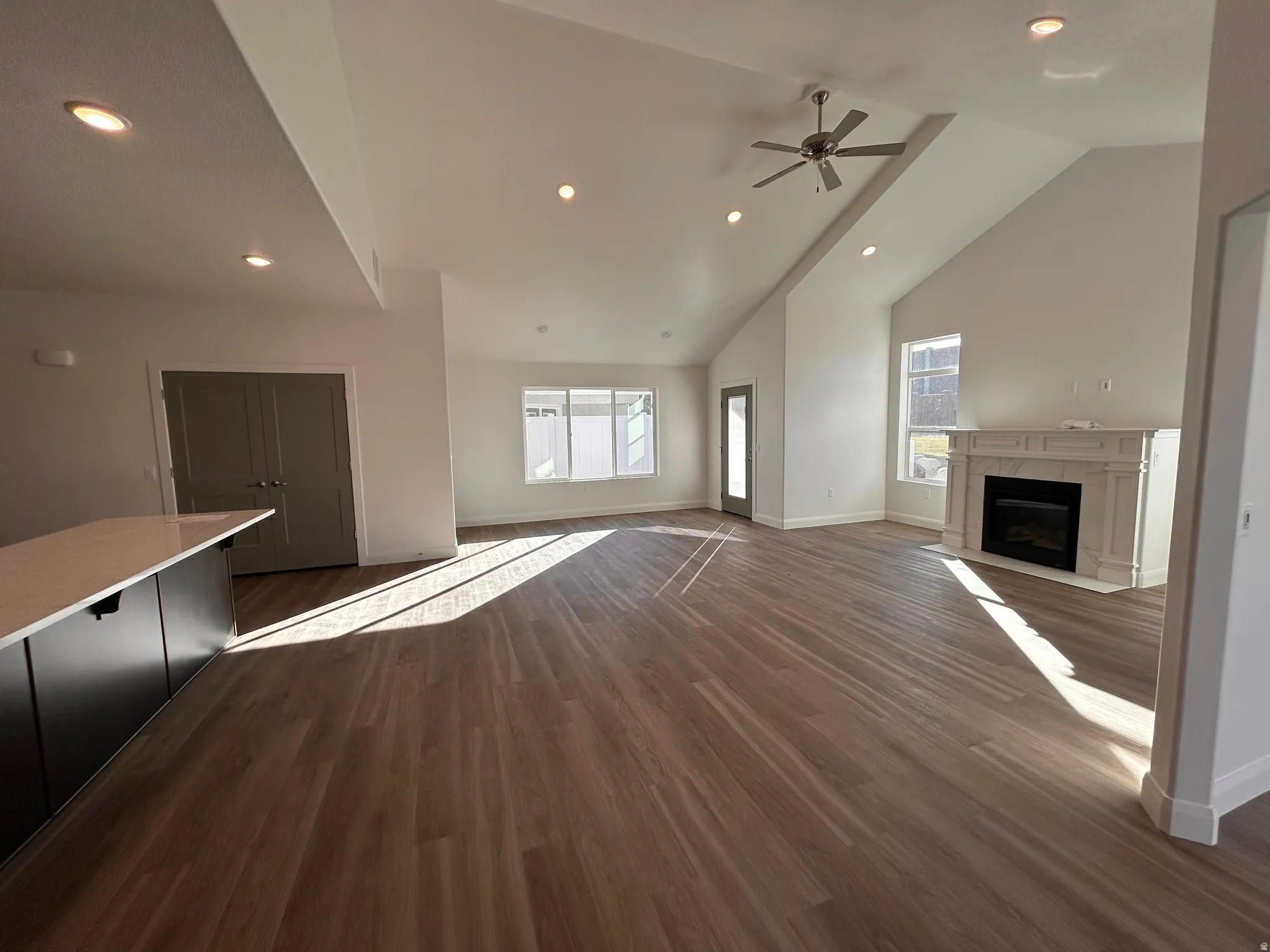 Unfurnished living room featuring recessed lighting, dark wood-type flooring, a fireplace, high vaulted ceiling, and ceiling fan