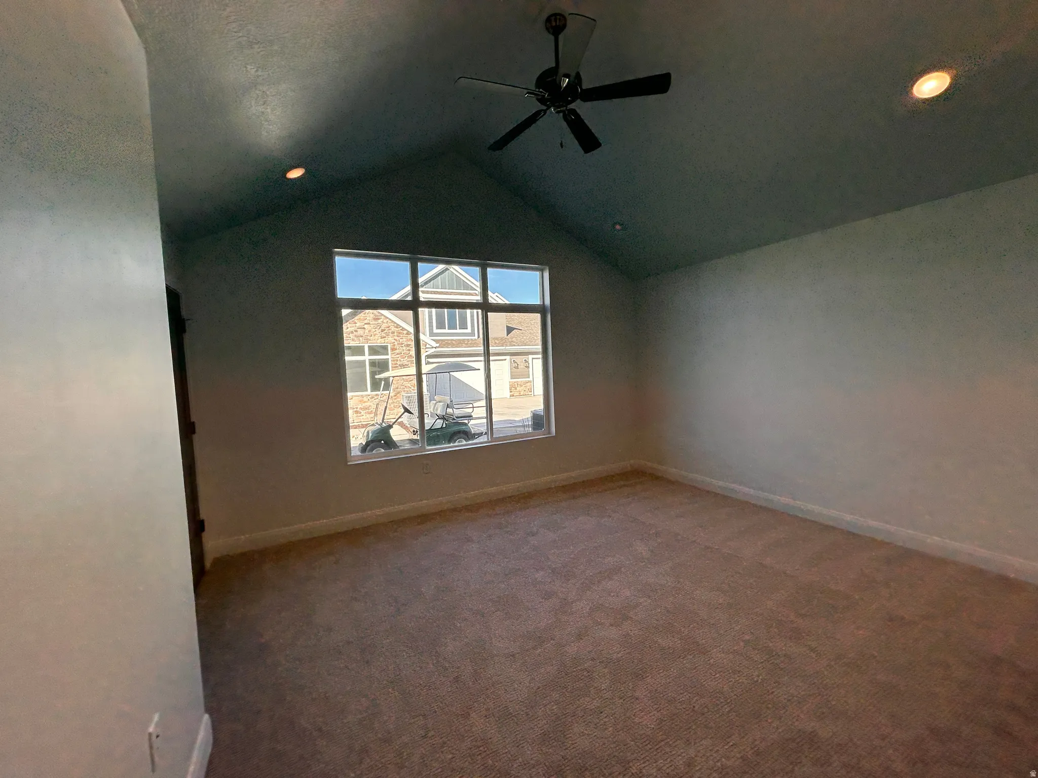 Carpeted spare room with vaulted ceiling and ceiling fan