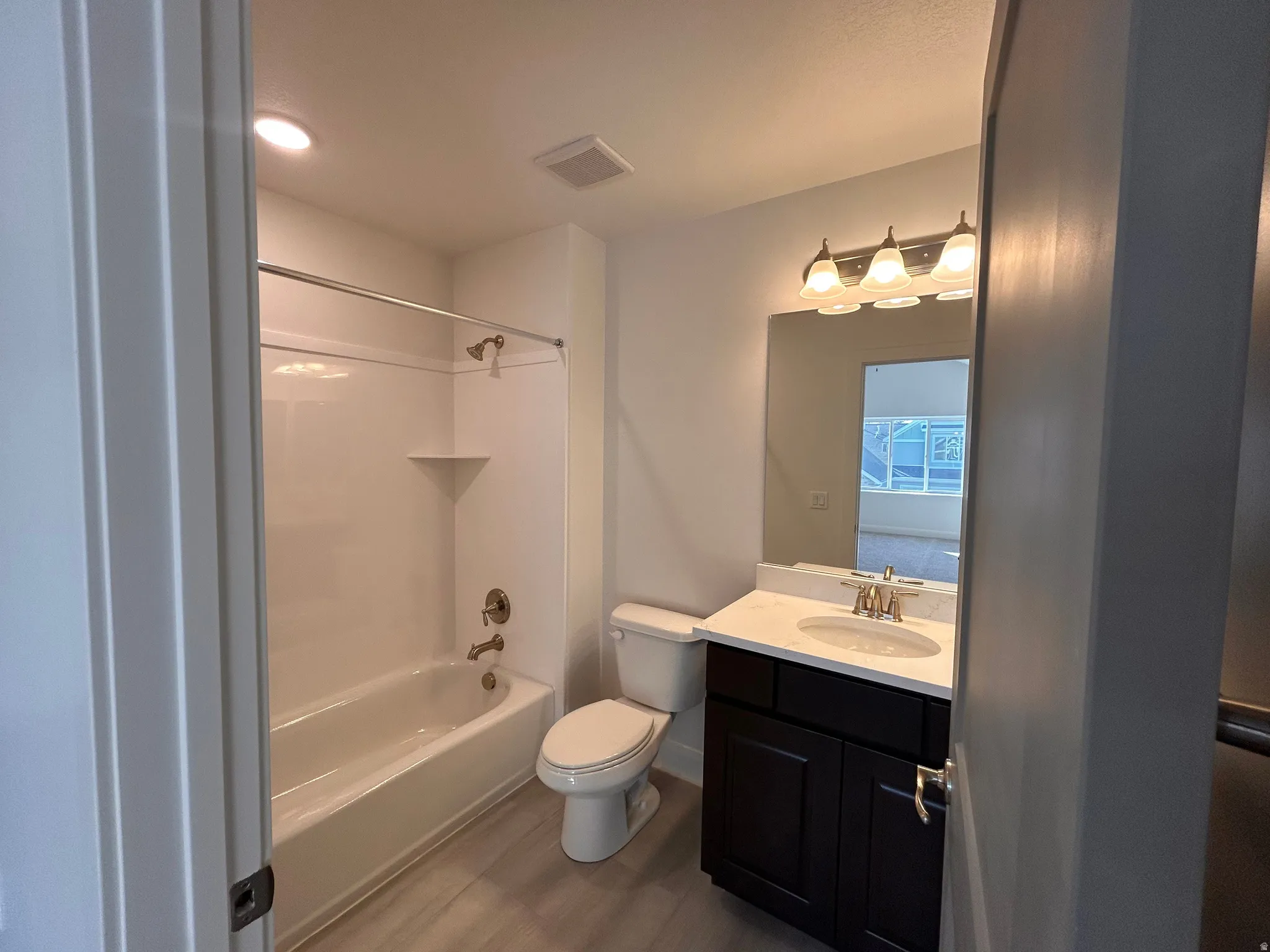 Bathroom featuring vanity, tub / shower combination, wood finished floors, and recessed lighting