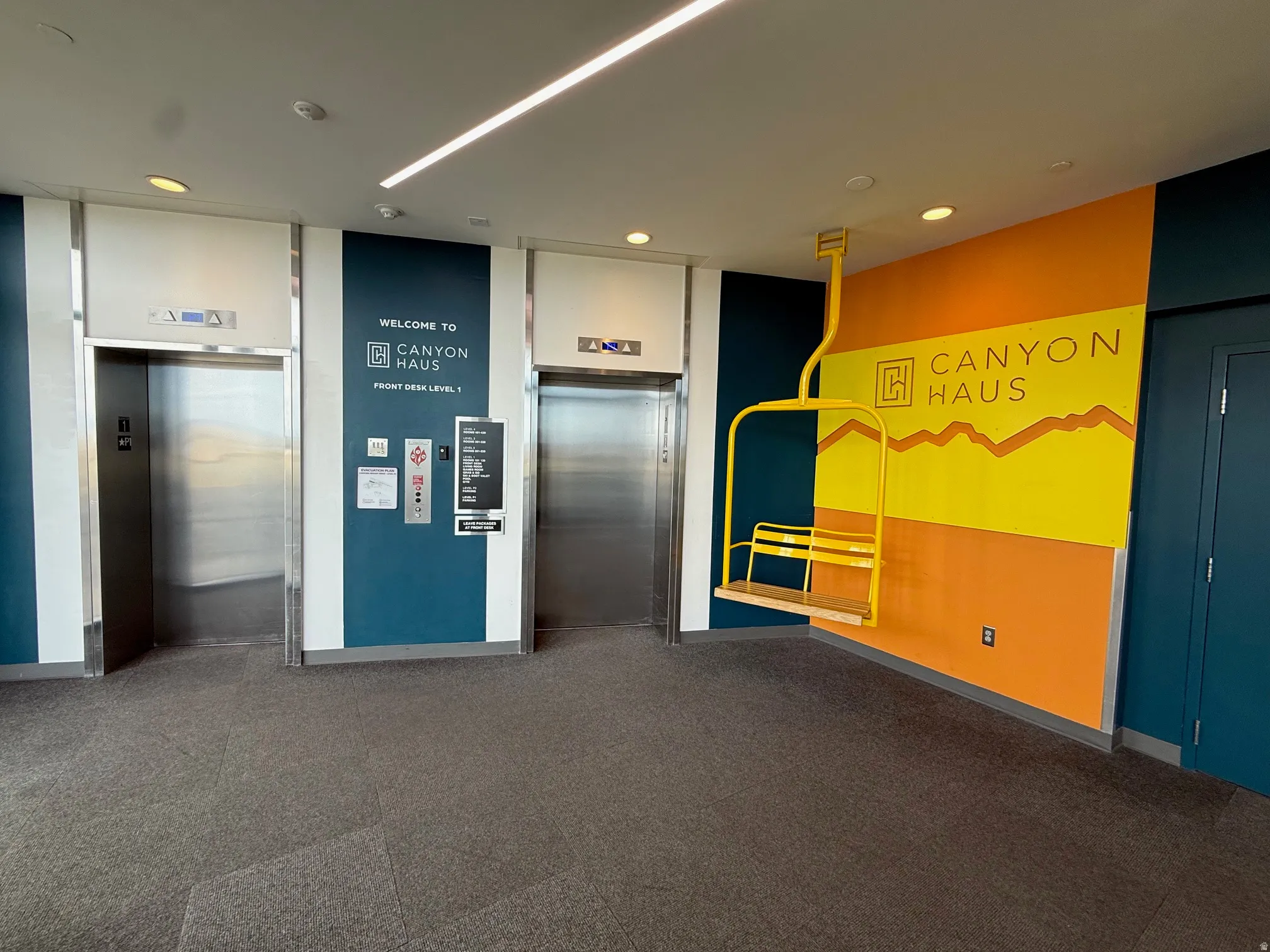 Lobby area featuring two stainless steel elevators, patterned carpet flooring, and integrated ceiling lighting