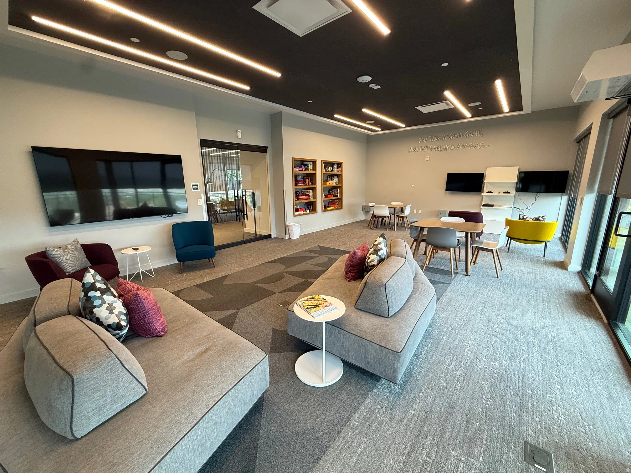 Spacious communal area featuring recessed lighting, a dark ceiling accent, carpeted flooring, a wall-mounted television, and floor-to-ceiling windows