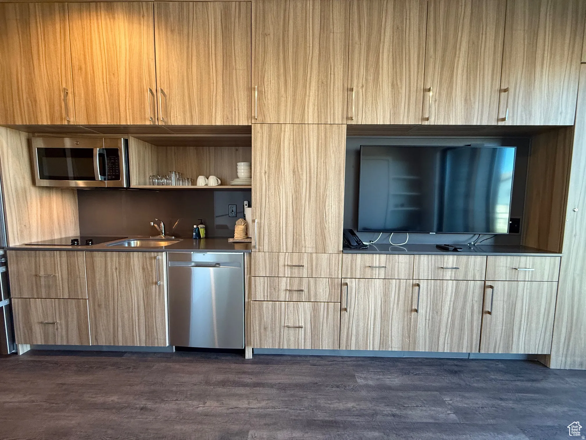 Bar with open shelves, appliances with stainless steel finishes, modern cabinets, dark wood finished floors, and dark countertops
