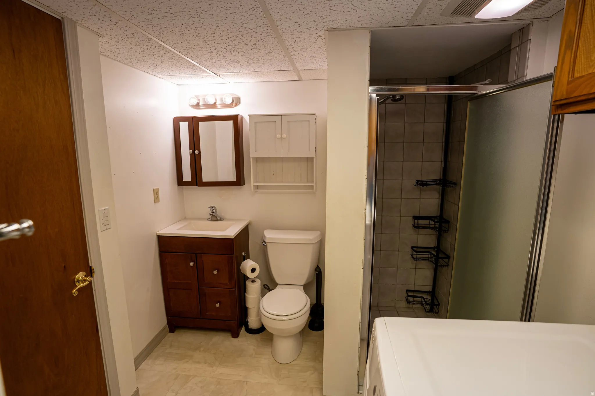 Second Bath (downstairs) featuring a shower stall, a drop ceiling, vanity, washer and dryer