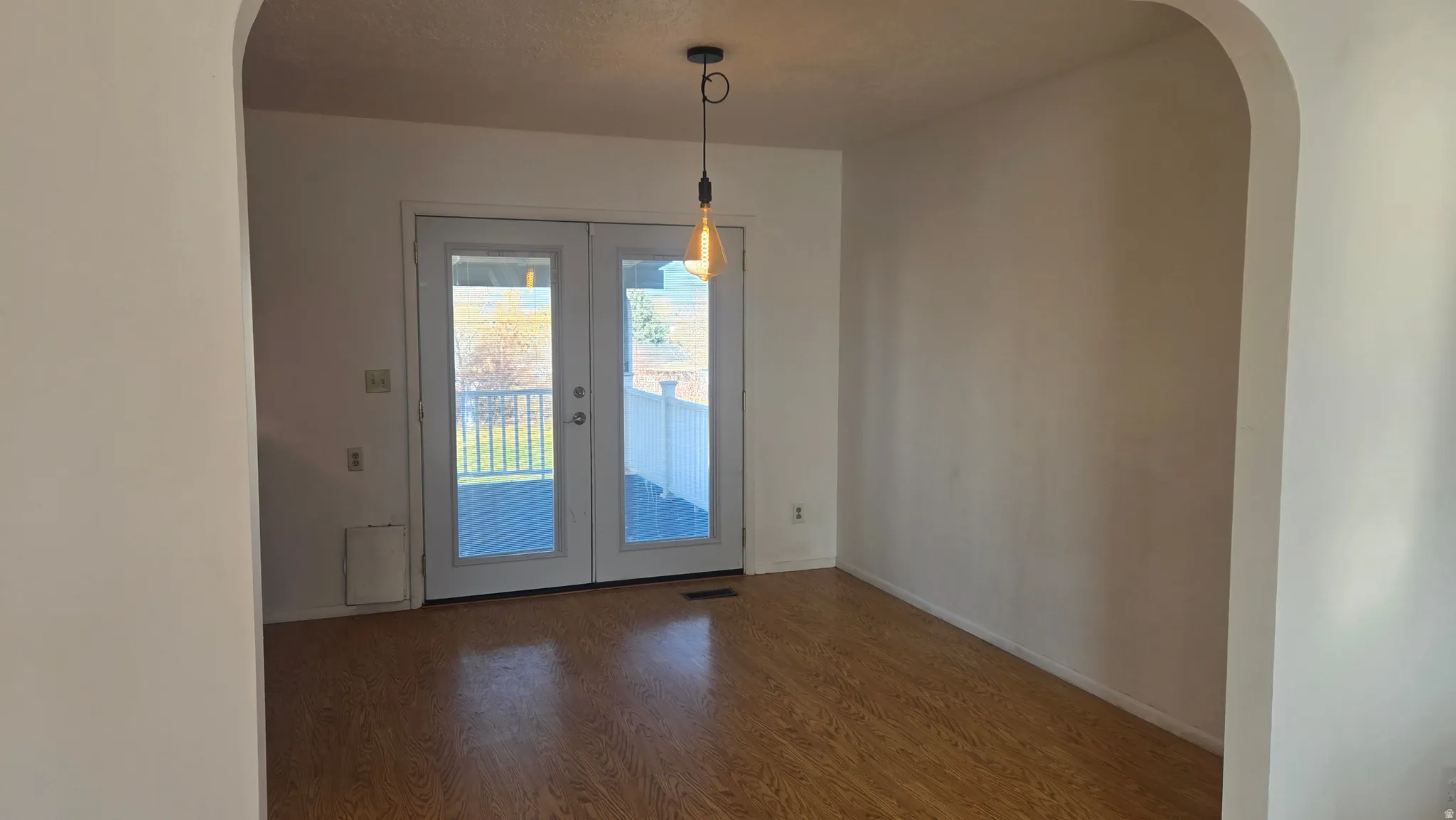 Dining area featuring arched walkways, French doors, and wood floors with a view of the covered back patio