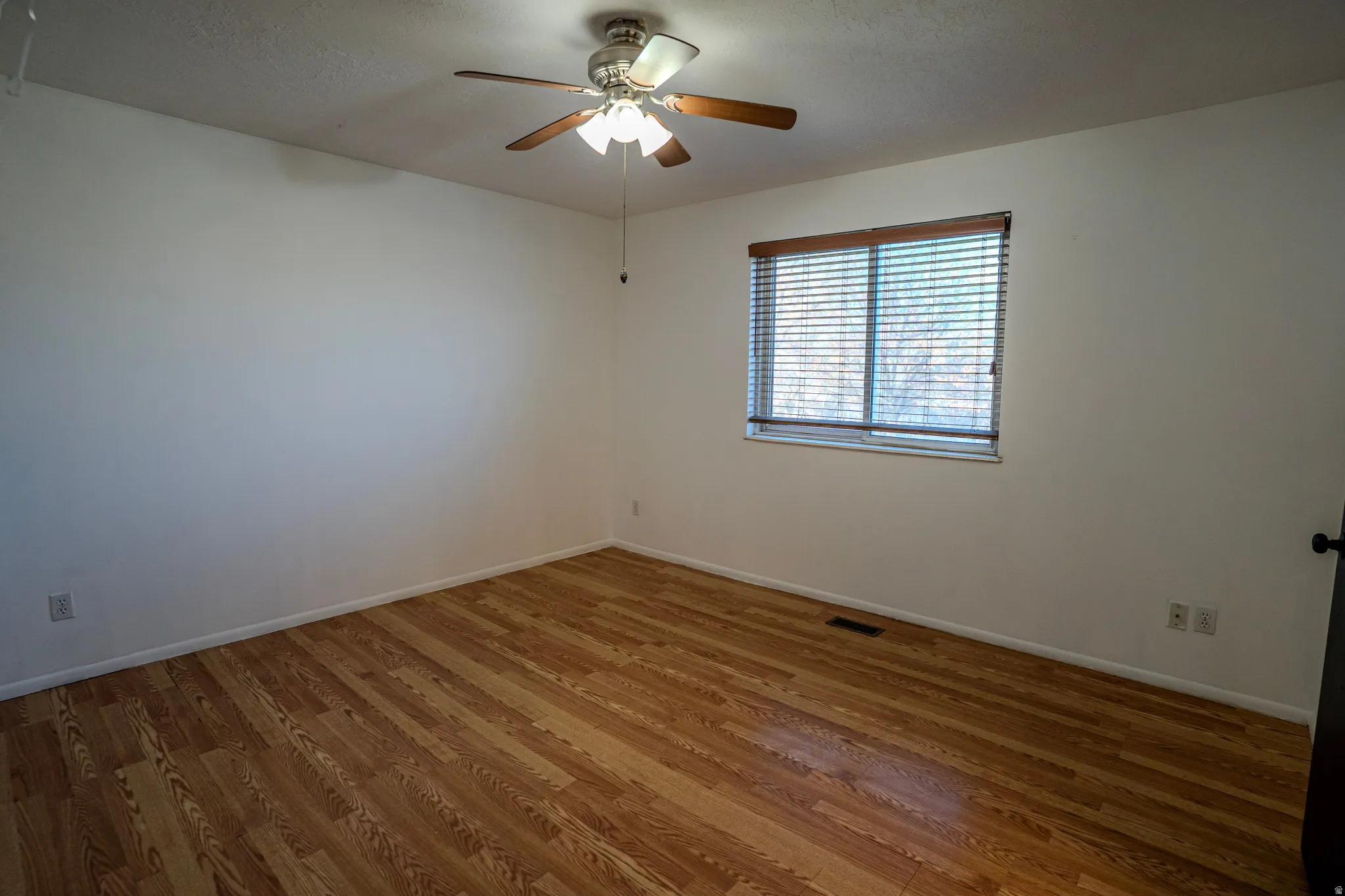 Primary Bedroom (upstairs) with light wood-style flooring, a textured ceiling, and ceiling fan