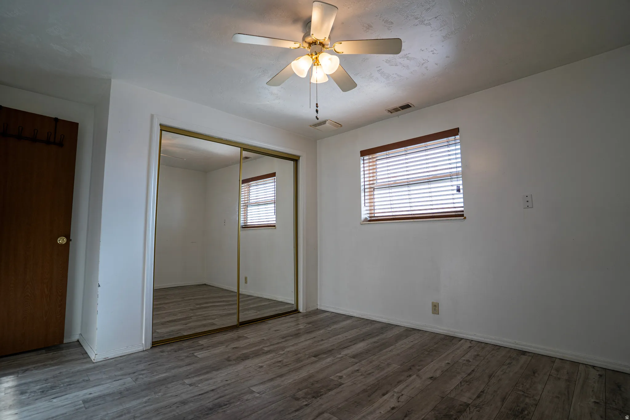 Window View of third bedroom (downstairs) featuring laminate floors, a closet, and a ceiling fan