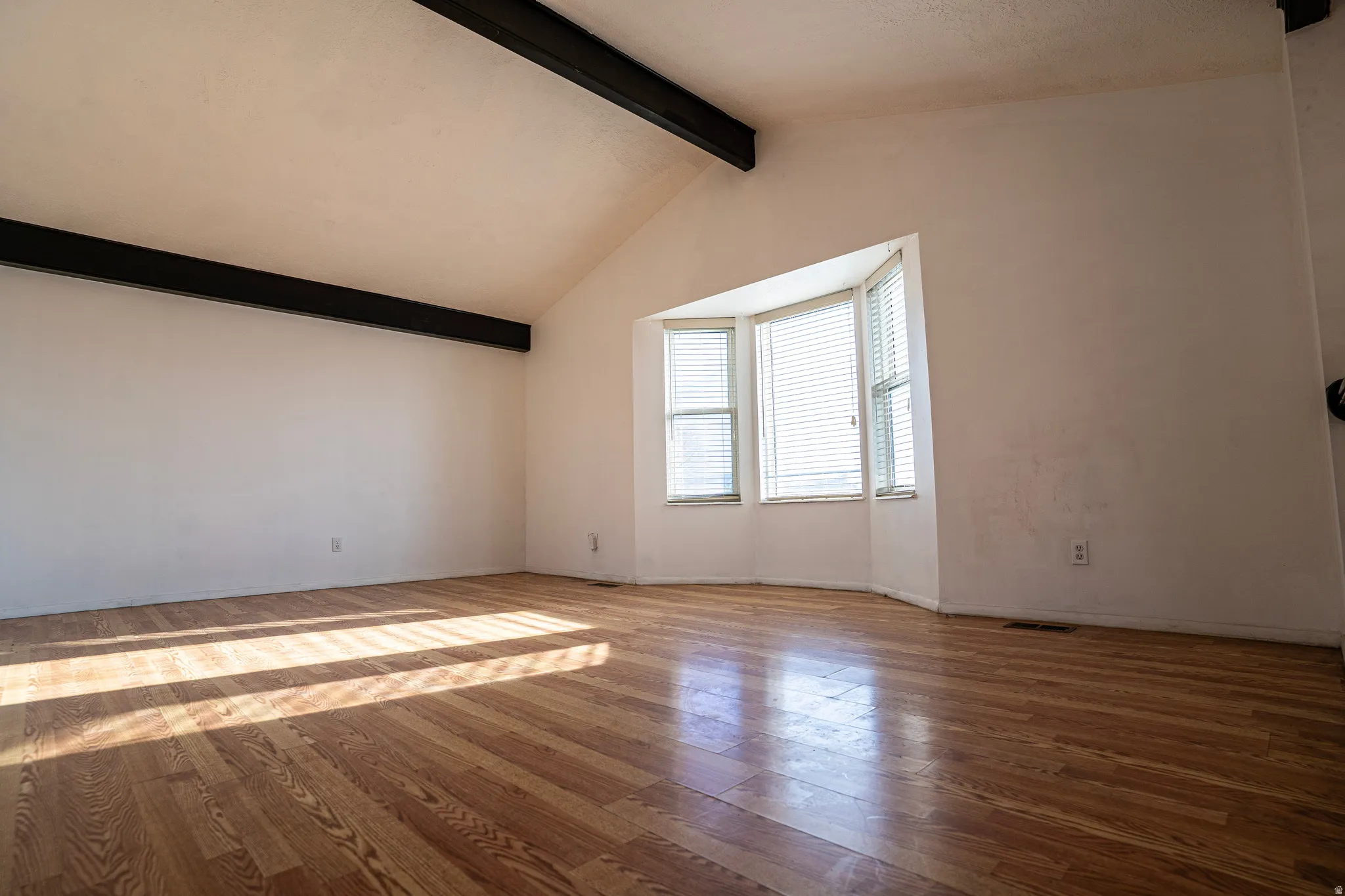 Front room featuring picture window, ceiling beams, wood flooring and baseboards