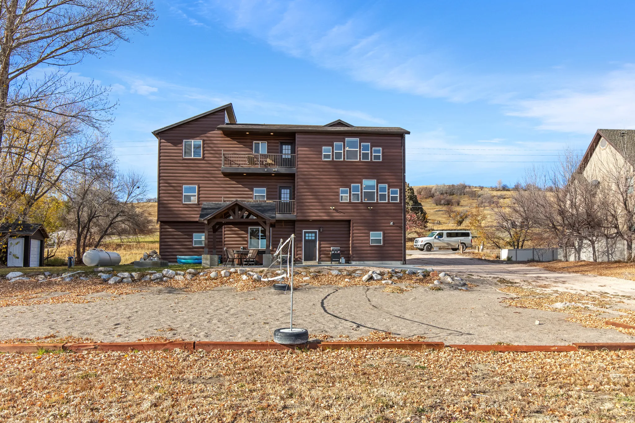View of front facade featuring faux log siding, a patio area, and a balcony