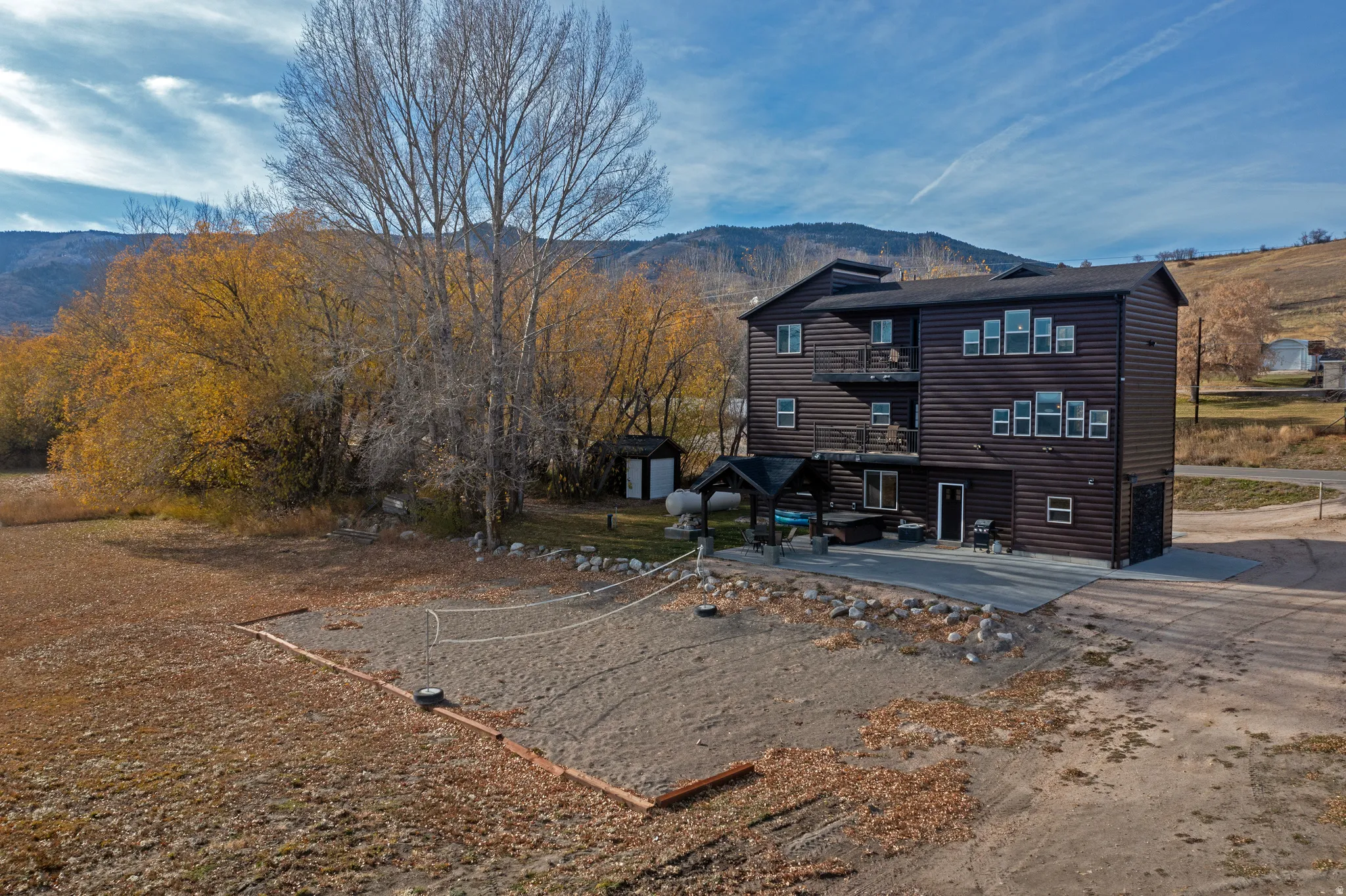 Back of house with a patio area, faux log siding, and a mountain view