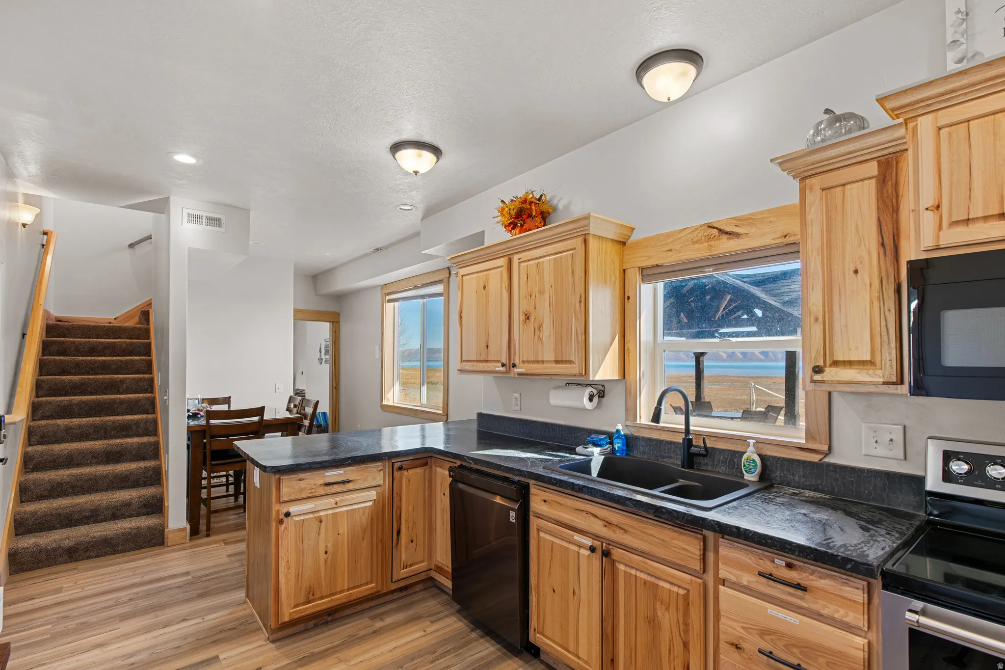 Kitchen featuring black appliances, healthy amount of natural light, light wood-type flooring, a peninsula, and recessed lighting