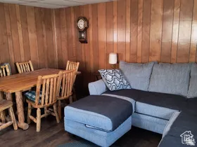 Living room with a drop ceiling, wood walls, and dark wood-type flooring