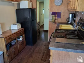 Kitchen featuring freestanding refrigerator, white microwave, dark wood-style flooring, and stainless steel electric stove