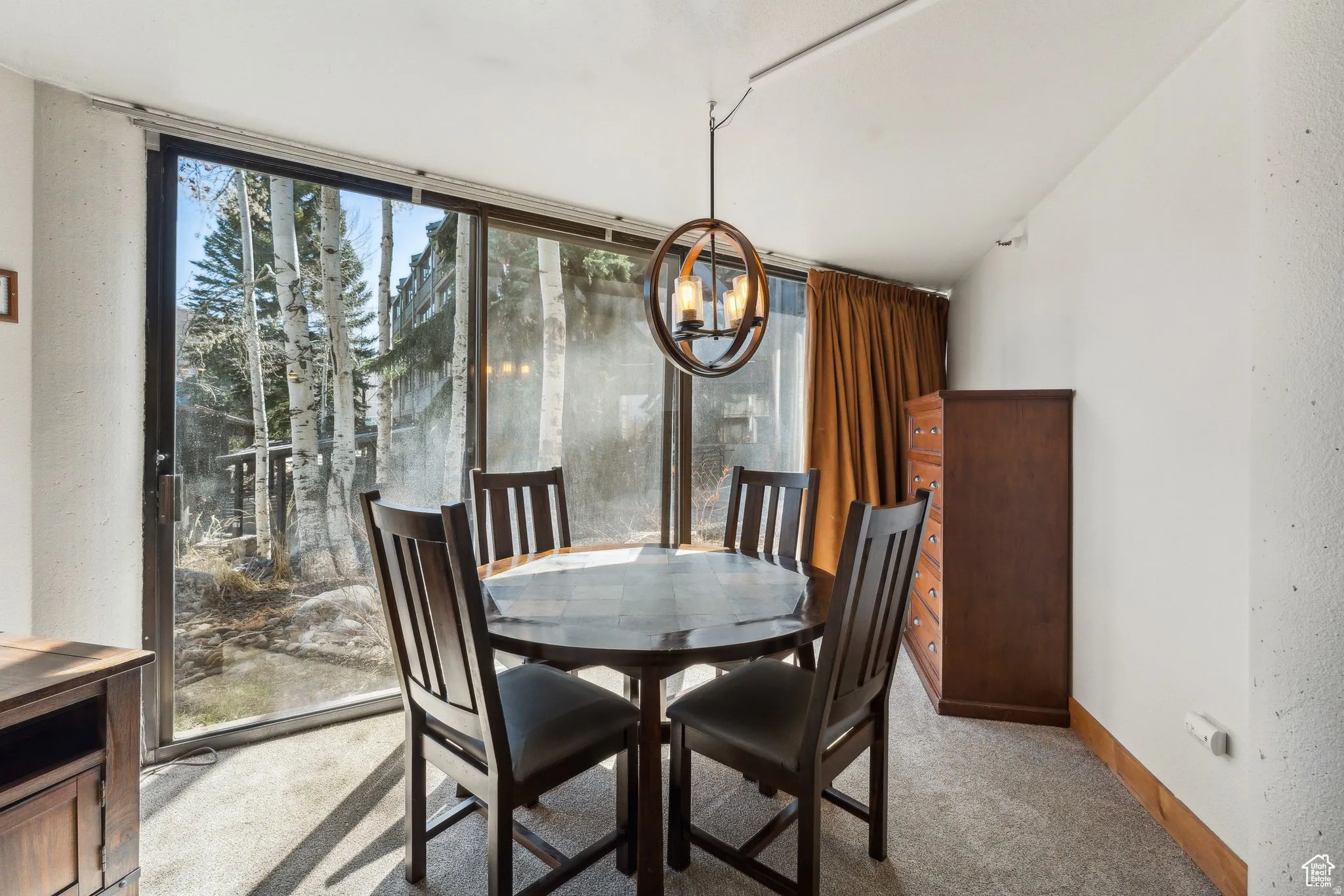 Dining area with a chandelier, carpet, floor to ceiling windows, and vaulted ceiling