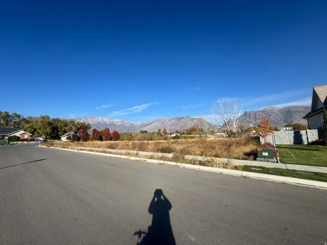 View of asphalt road featuring a mountain view, sidewalks, and curbs