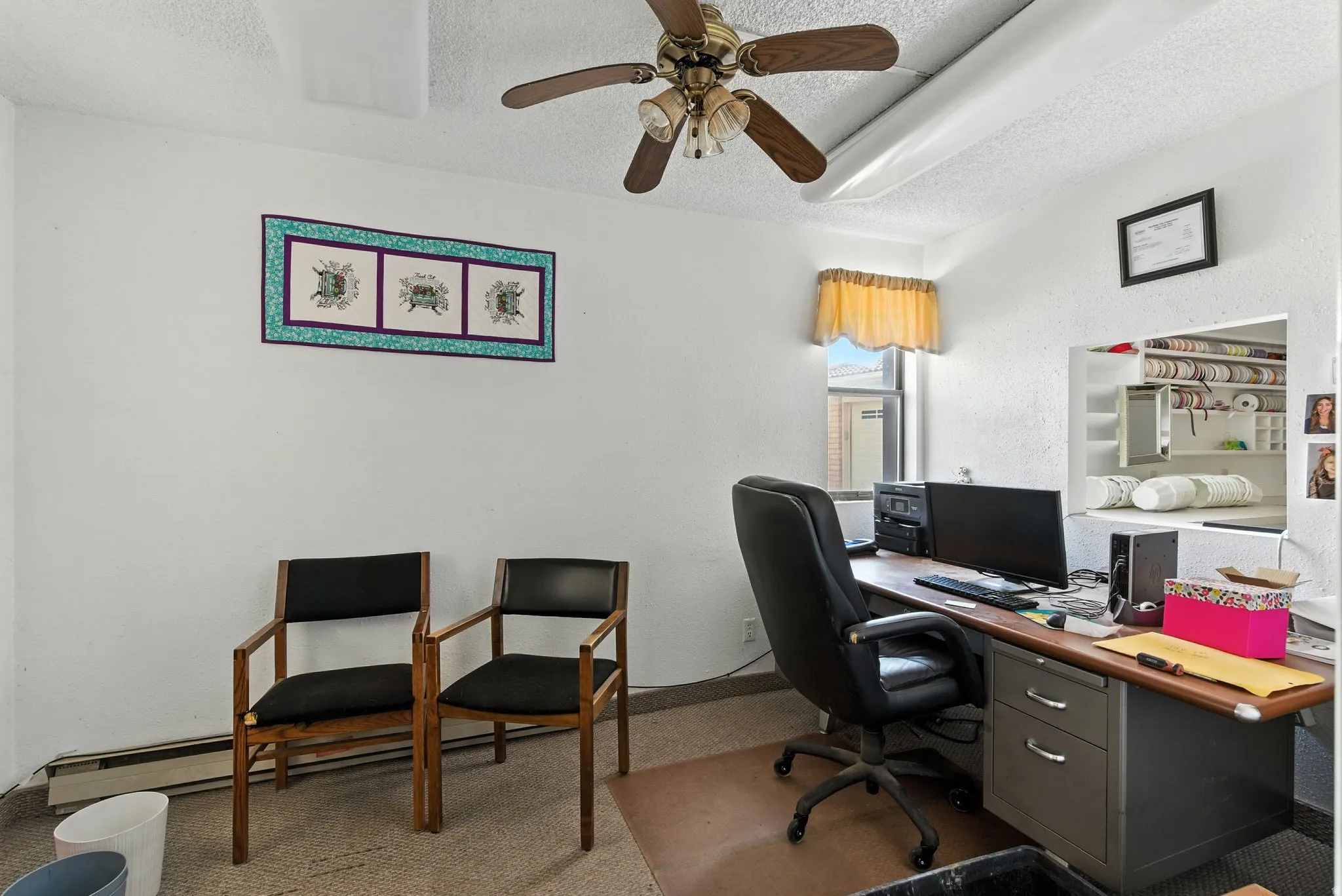 Home office with a textured ceiling, ceiling fan, carpet floors, and a textured wall