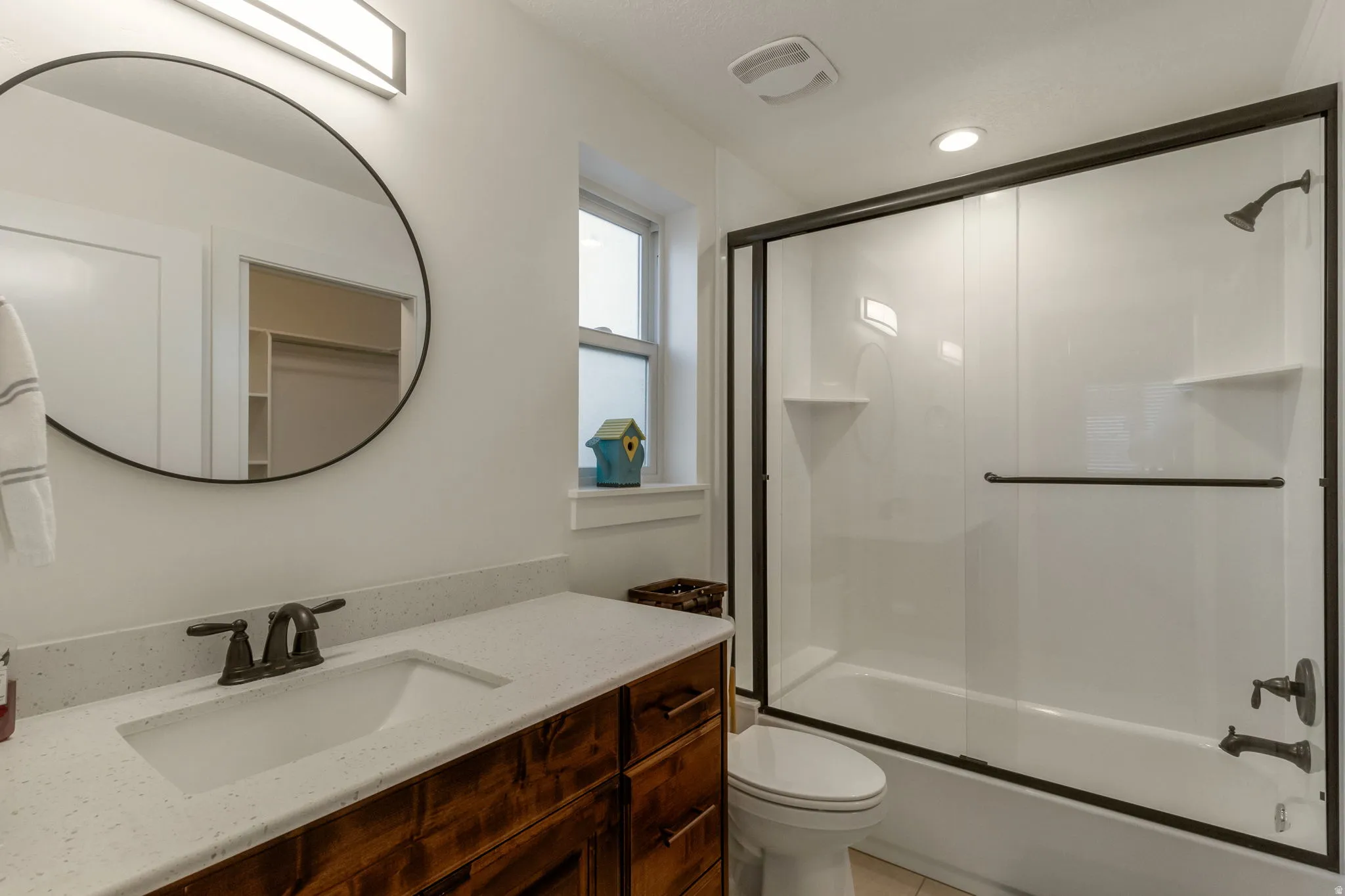 Bathroom with vanity, shower / bath combination with glass door, and light tile patterned floors