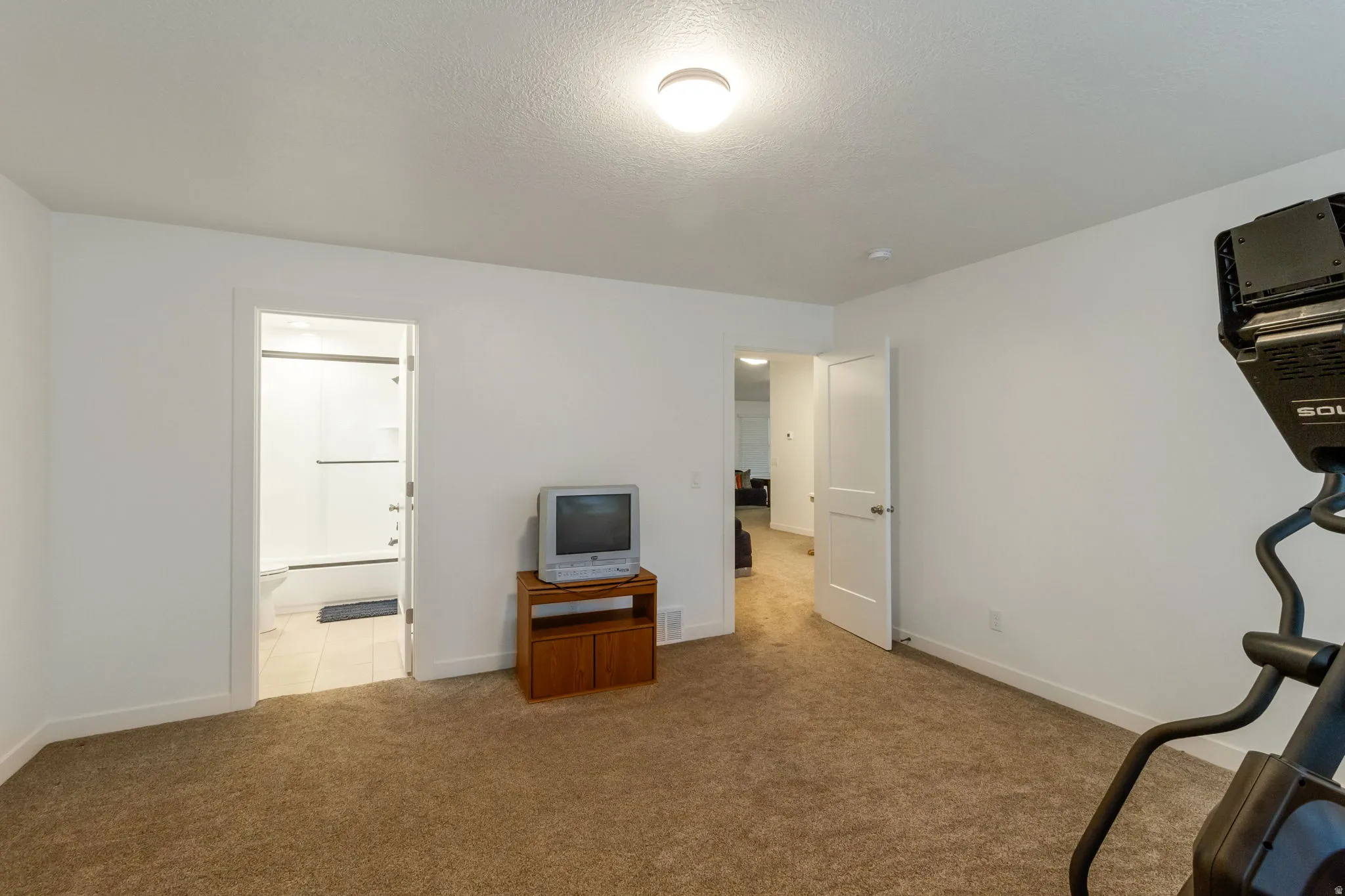 Exercise area with light colored carpet and a textured ceiling
