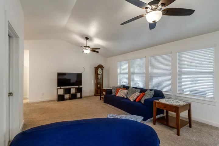 Living area with light carpet, lofted ceiling, and a ceiling fan