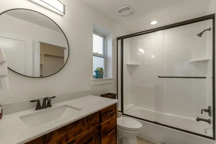 Bathroom with vanity, shower / bath combination with glass door, and light tile patterned floors