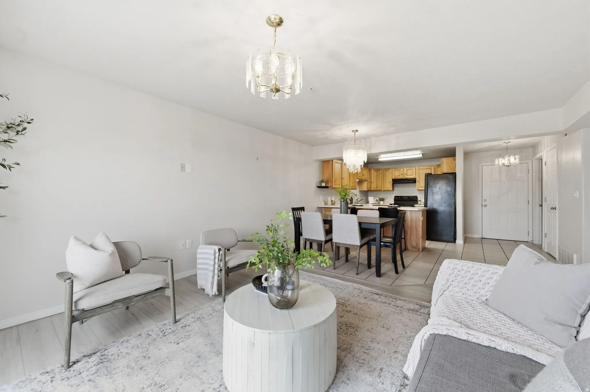 Open-concept living space featuring wood-finish flooring, a contemporary chandelier, and a dining area with a modern light fixture