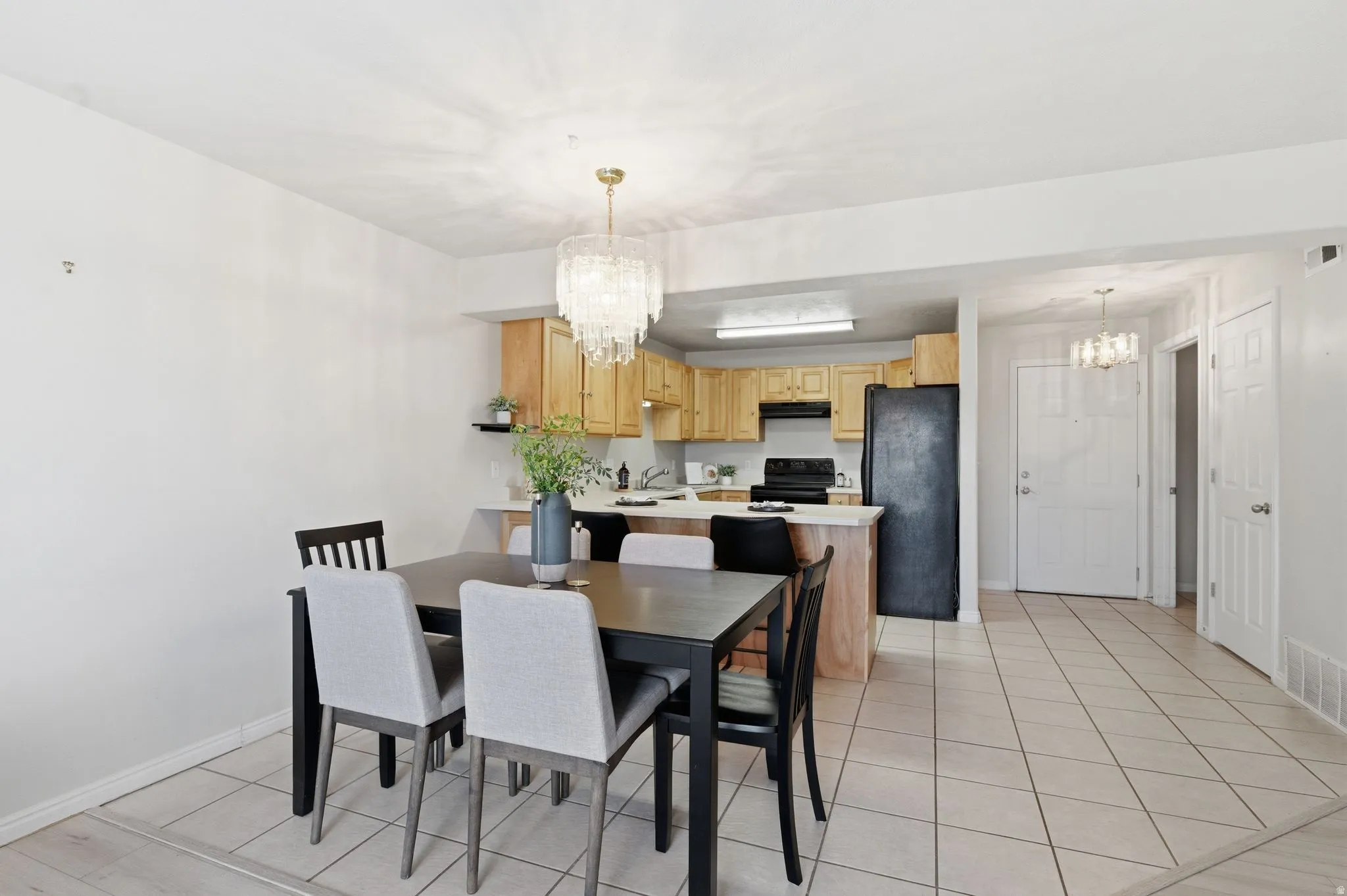 Open-concept dining area featuring a crystal chandelier, light tile flooring, and a breakfast bar