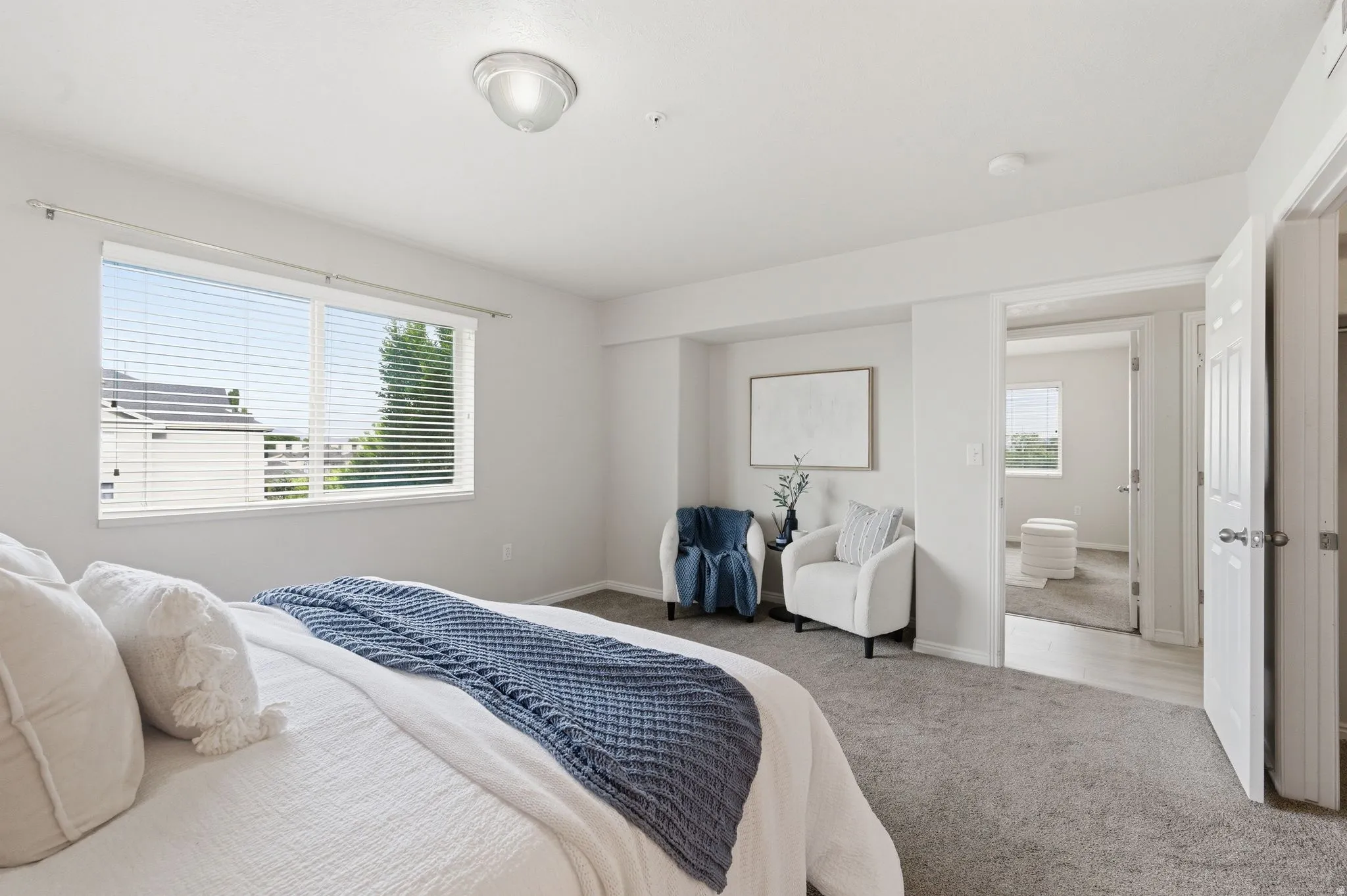 Primary bedroom featuring neutral carpeting, a large window with horizontal blinds, and a light-colored ceiling
