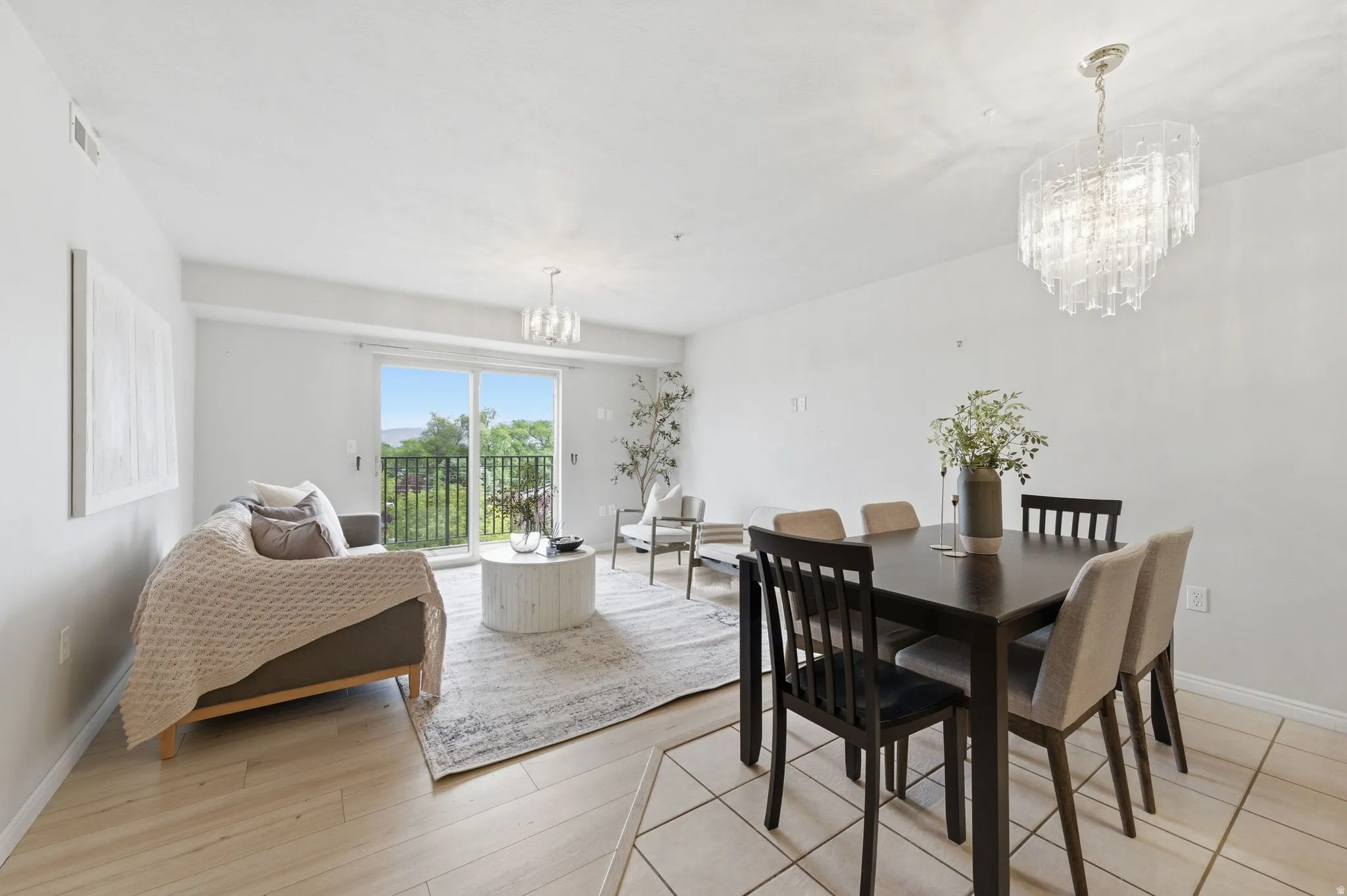Open-concept living and dining area featuring light wood-finish flooring, white walls, and a sliding glass door to a balcony