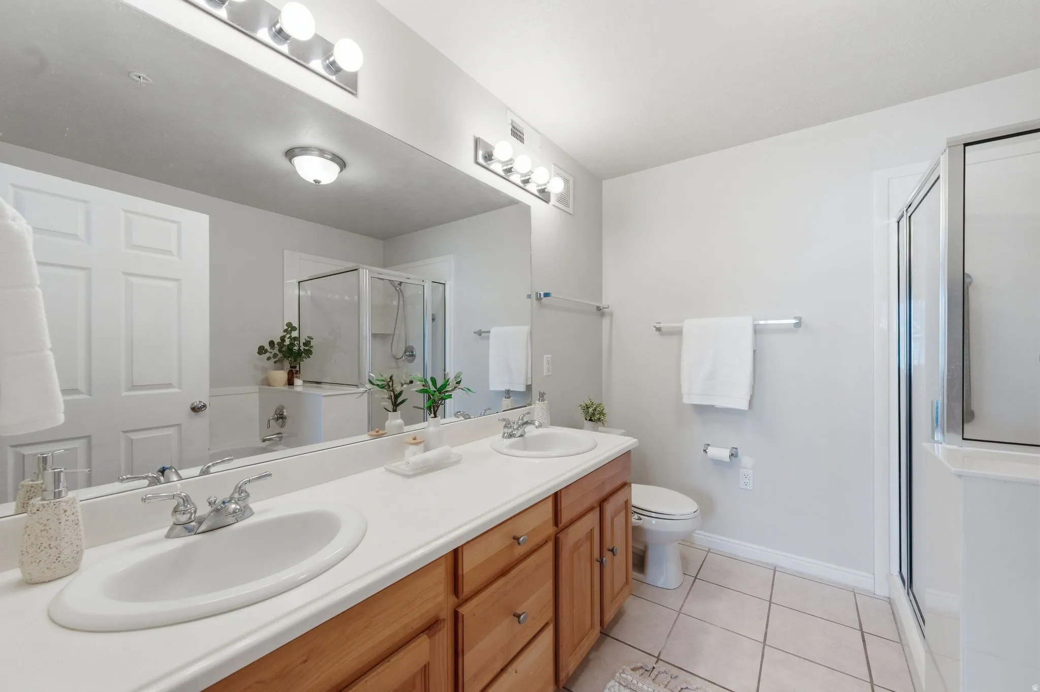 Primary bathroom featuring dual vanity with wood-finish cabinetry and chrome fixtures