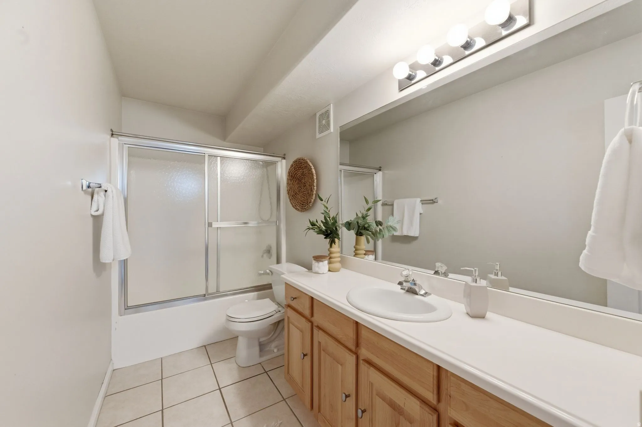 Guest bathroom featuring a light wood-finish vanity with a white countertop and integrated sink