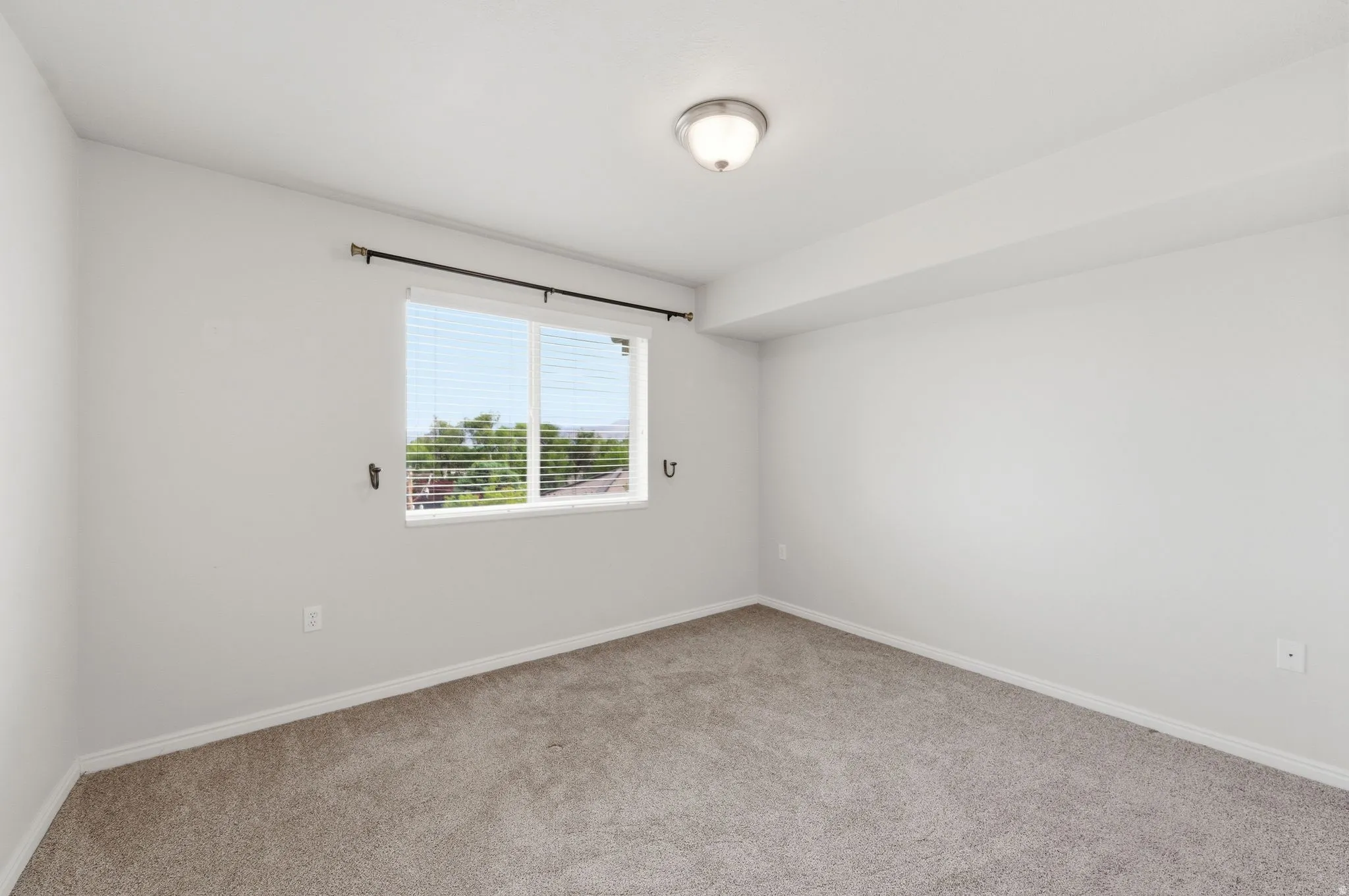 Bedroom featuring a double-pane window with horizontal blinds, a ceiling-mounted light fixture, and white painted walls with matching baseboards