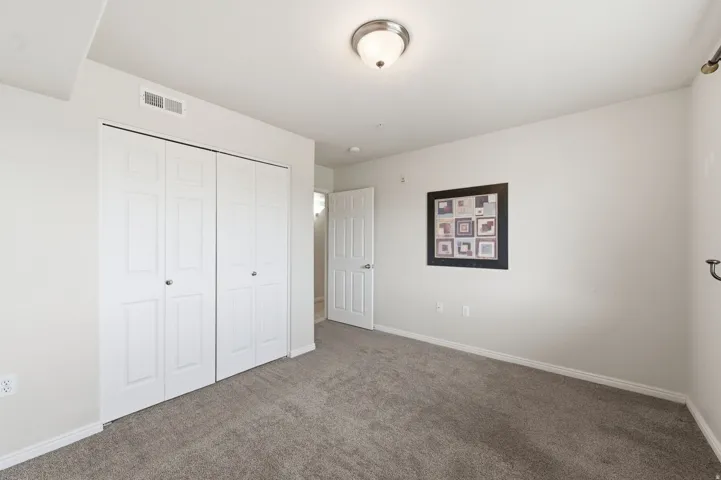 Bedroom featuring neutral wall tones complement the white bi-fold closet doors and trim