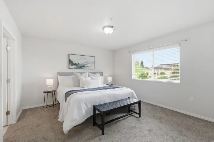 Primary bedroom featuring neutral wall tones, a large window with blinds, and a ceiling-mounted light fixture