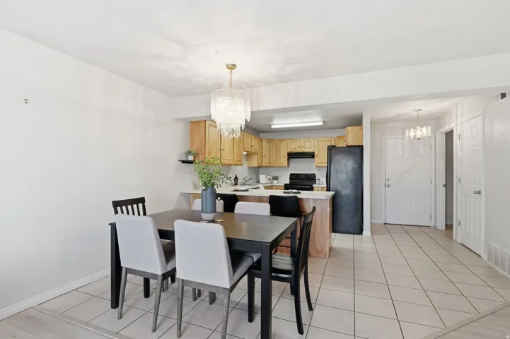 Open-concept dining area featuring a crystal chandelier, light tile flooring, and a breakfast bar