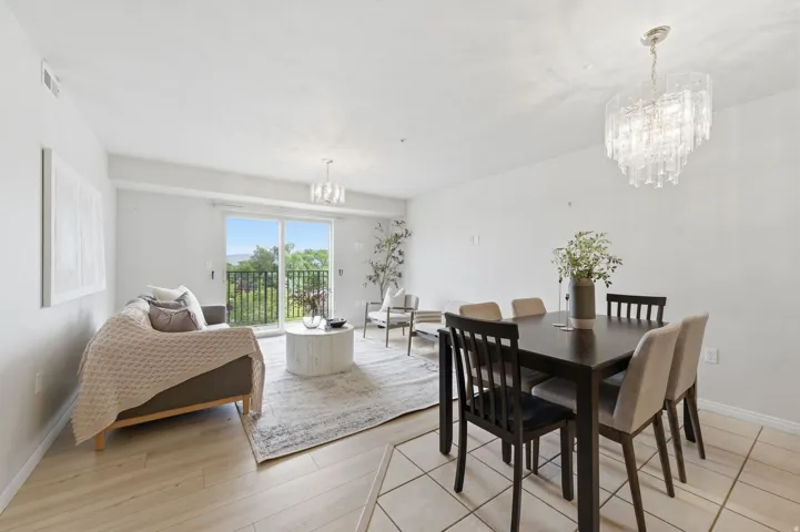 Open-concept living and dining area featuring light wood-finish flooring, white walls, and a sliding glass door to a balcony
