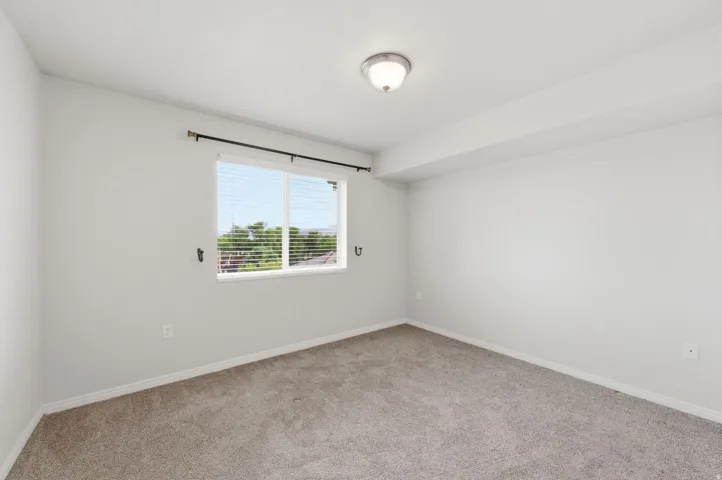 Bedroom featuring a double-pane window with horizontal blinds, a ceiling-mounted light fixture, and white painted walls with matching baseboards